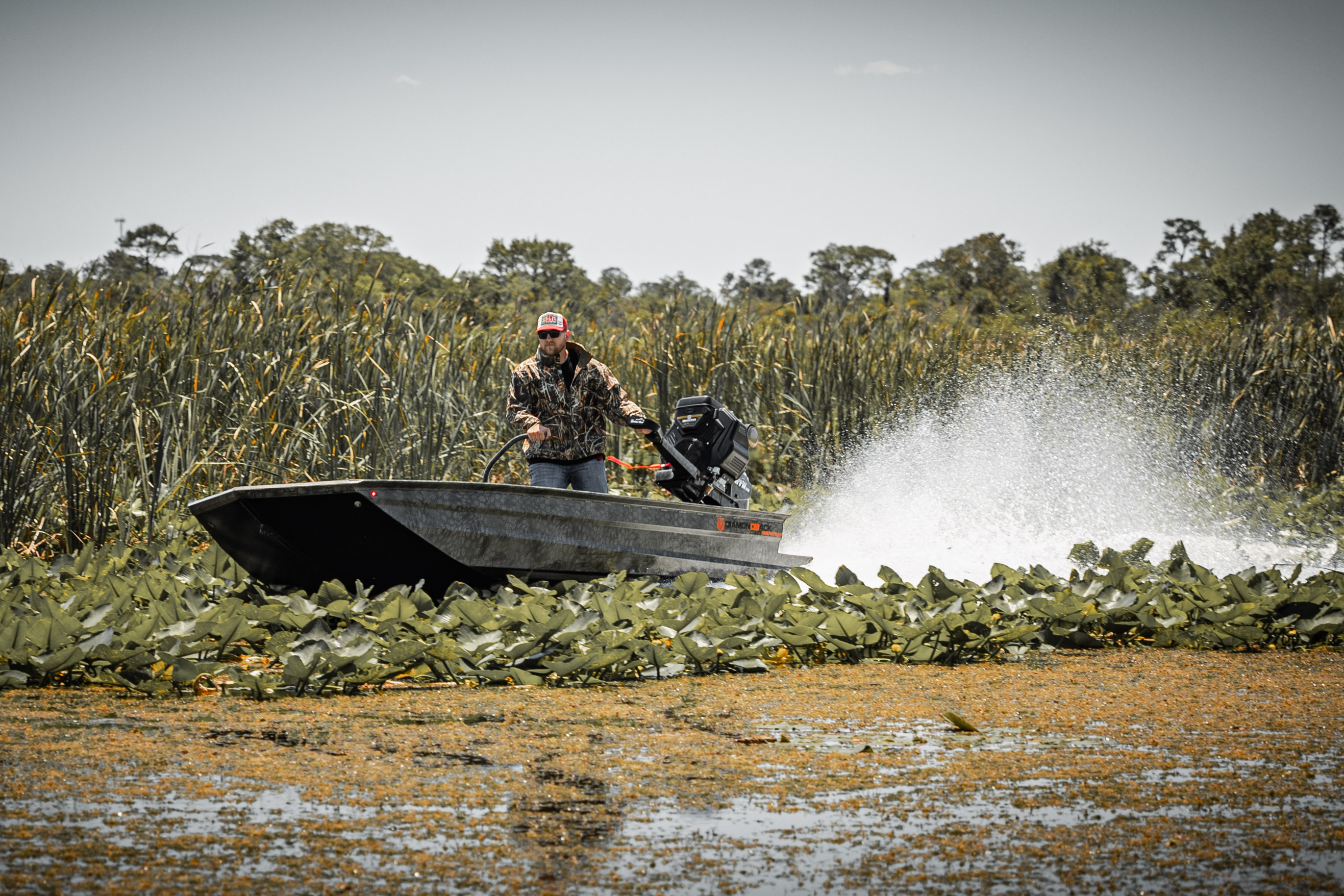 Diamondback mud boat blasting through shallow water and lily pads